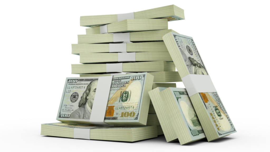 Stacks of $100 US dollar bills arranged in piles, with some bundles leaning against each other, set against a white background.