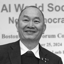 A man in a suit smiles in front of a sign with partially visible text about an AI World Society event in Boston. The background text mentions the date September 25, 2024.