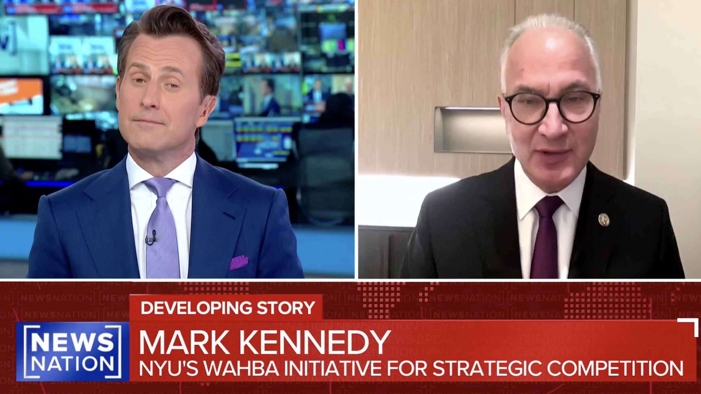 Two men appear in a split-screen TV news segment. The man on the left wears a blue suit and pink tie; the man on the right wears glasses, a dark suit, and a red tie. News chyron reads: Mark Kennedy, NYU’s Wahba Initiative for Strategic Competition.