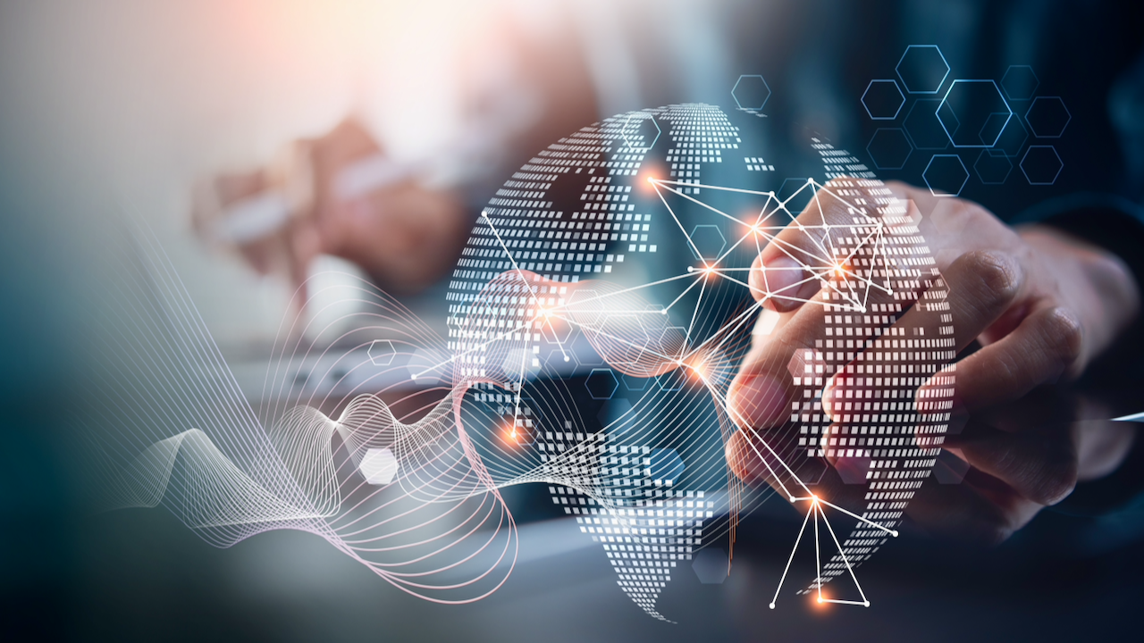 A person uses a touchscreen device with a digital globe, glowing network lines, and geometric shapes overlaying the image, representing global digital connections and technology.